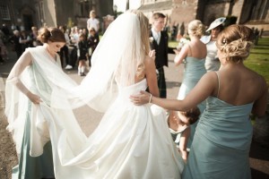 bridesmaids help the bride with her dress
