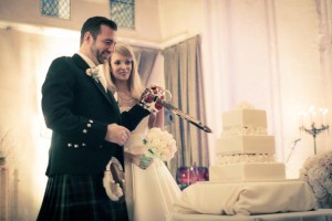 the bride and groom cut their wedding cake with a large sword