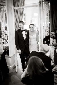 Bride & groom walking into dinner reception to their guests with large smiles on their faces