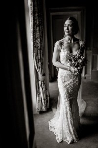 black and white full length shot of bride looking at the camera in soft window light