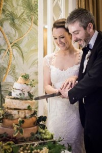 bride and groom enjoying cutting their beauitful cake made from wheels of cheese