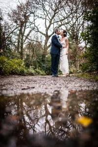 the bride and groom are seen along with their reflection in a puddle on a crisp winters day