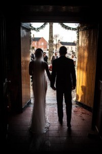 the bride and groom walk out of the church together in warm evening light