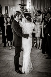 the bride wraps her arm around her groom and elegantly caresses him while they enjoy their first dance