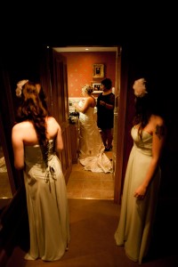 bridesmaids look on as bride gets ready