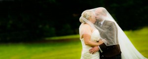 bride and groom kiss under veil on windy day