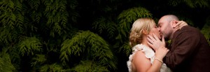 bride and groom kiss in bushes