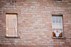 wedding guest waves from window at dalhousie castle.