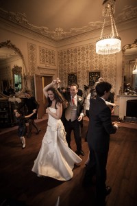 ceilidh dancing beneath chandelier at wedding at drummuir castle