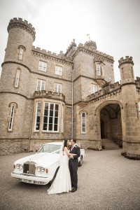 bride and groom kiss by wedding car outside drummuir castle