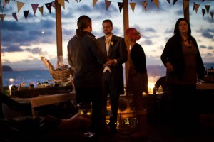 wedding guests talk beneath bunting overlooking beach at ravensheugh log cabin