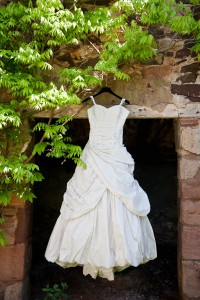 wedding dress hanging up outside bside old wall and tree