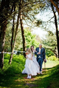 bride arrives at outdoor wedding with father and flowergirl