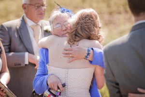 mother hugs bride at beach wedding