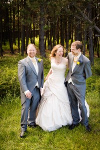 bride and groom with best man at outdoor wedding on windy day