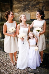 bride with bridesmaids and flower girl laughing