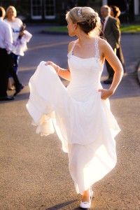 bride holds up dress from ground