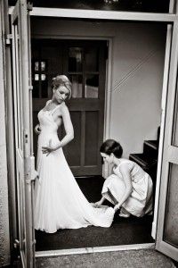 bridesmaid sorts bride's train and helps her get ready