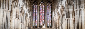 The bride and groom kiss with the magnificent stained glass windows of Dunblane Cathedral